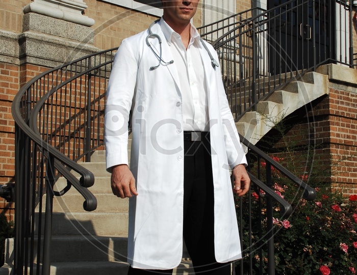 A male doctors wearing white coat with stethoscope at the staircase