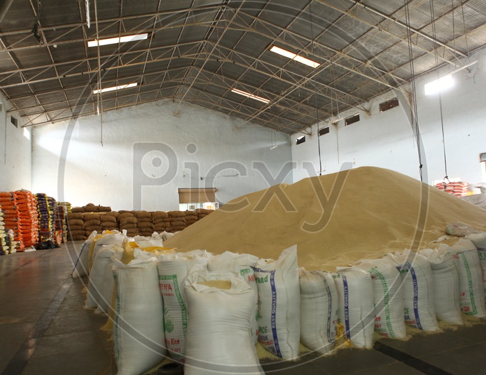 A big rice heap lined with rice bags in a Godown of a rice mill
