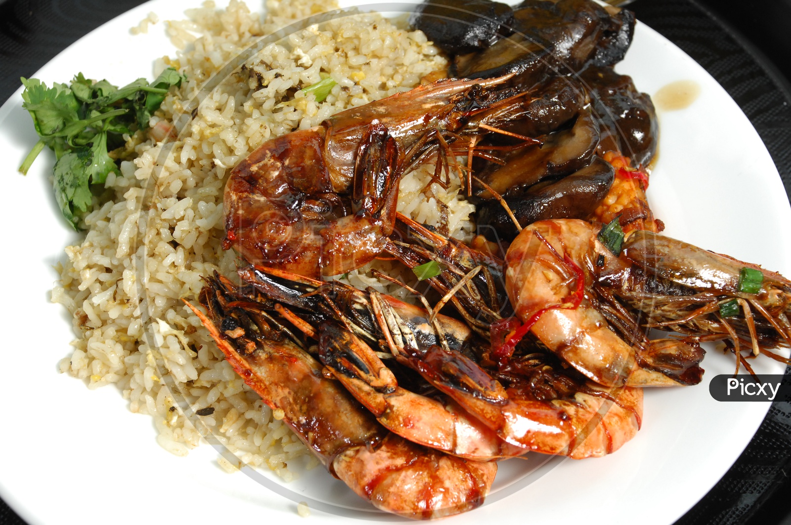 Cooked shrimps along with fried rice served in a white plate