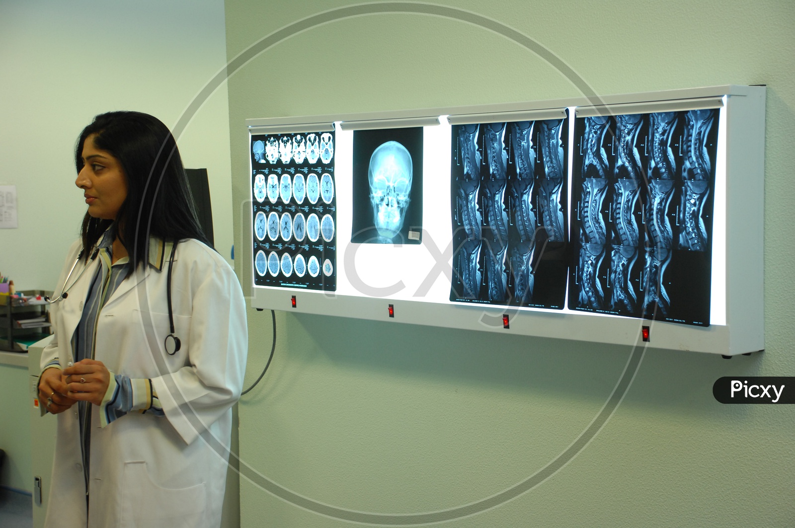 Doctor with  white coat and stethoscope checking the x-rays of the human skull