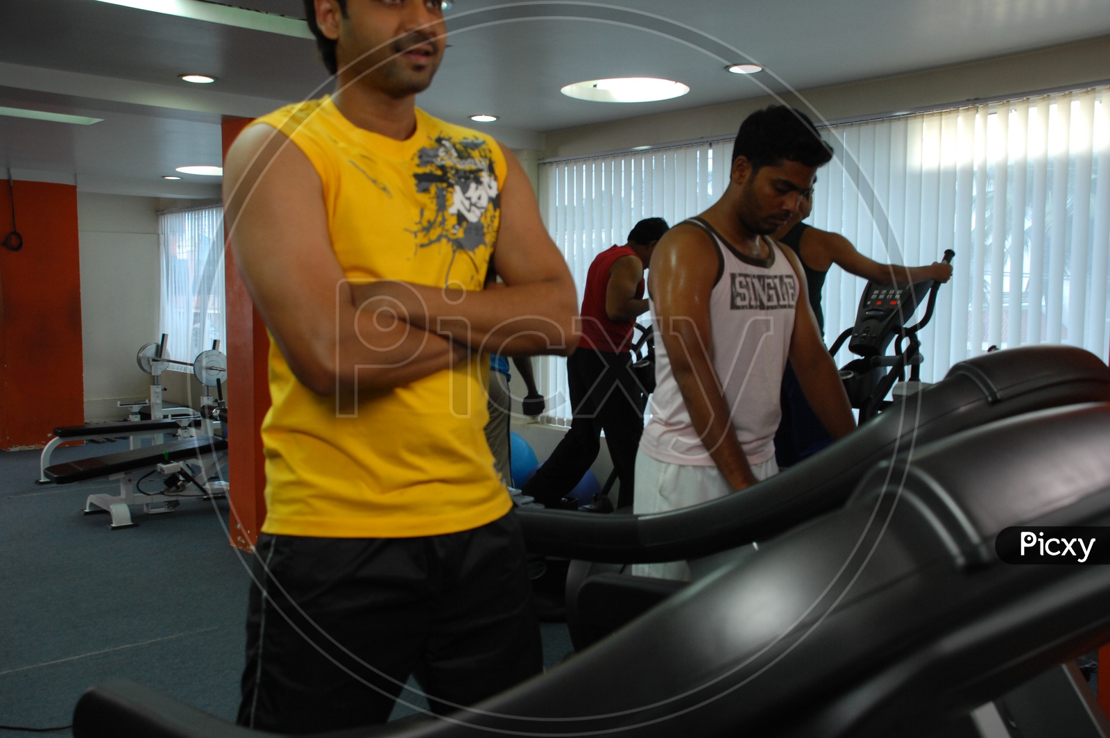 Actor Sumanth holding his hands alongside the treadmill in a Gym