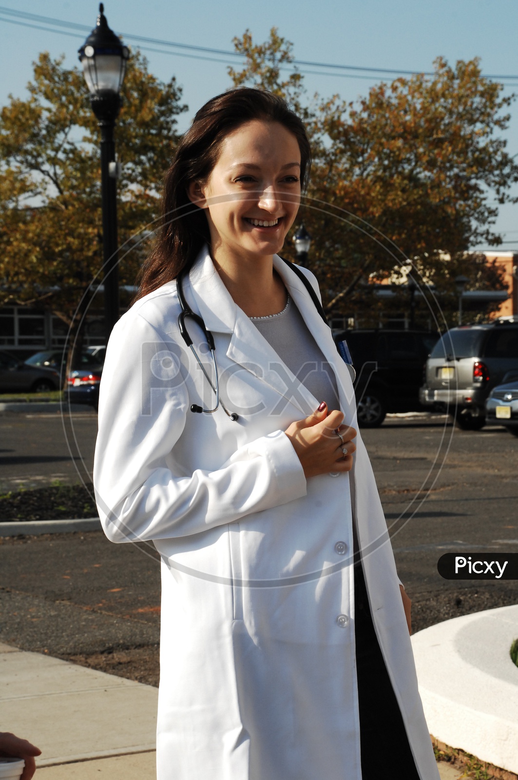 A smiling female doctor with stethoscope wearing a long white coat