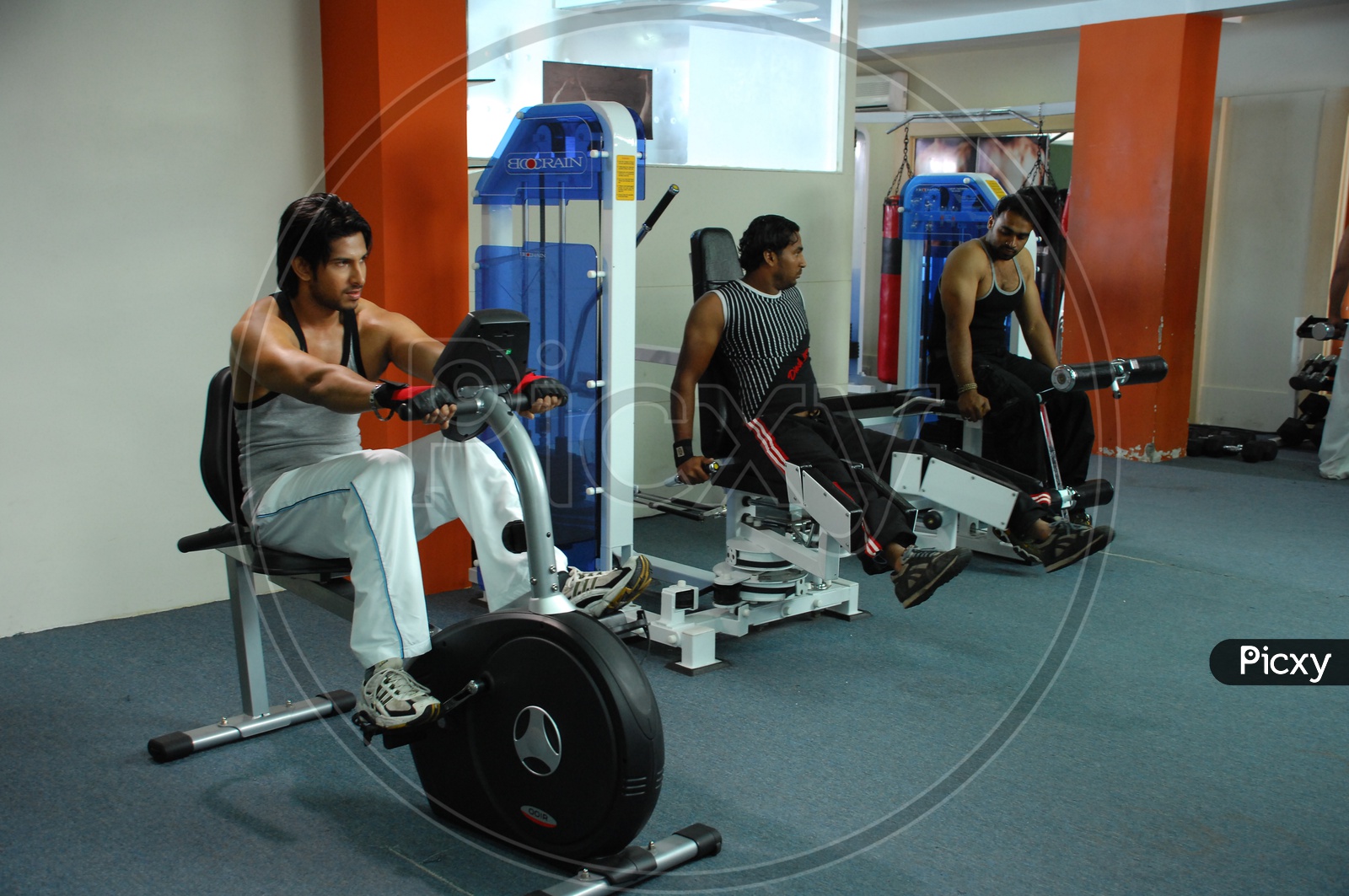 Actor Vamsi Krishna doing the upright bike exercise alongside the two other men in a Gym