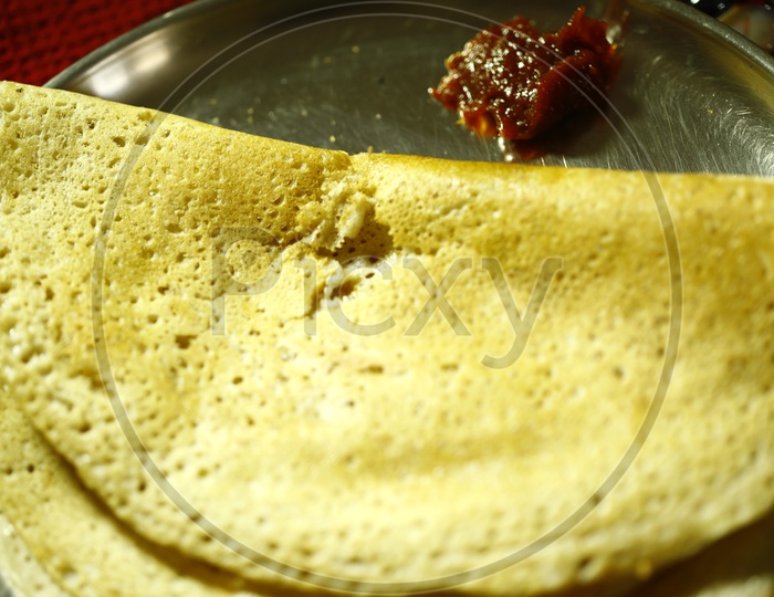 Dosa with a pickle served in a steel plate