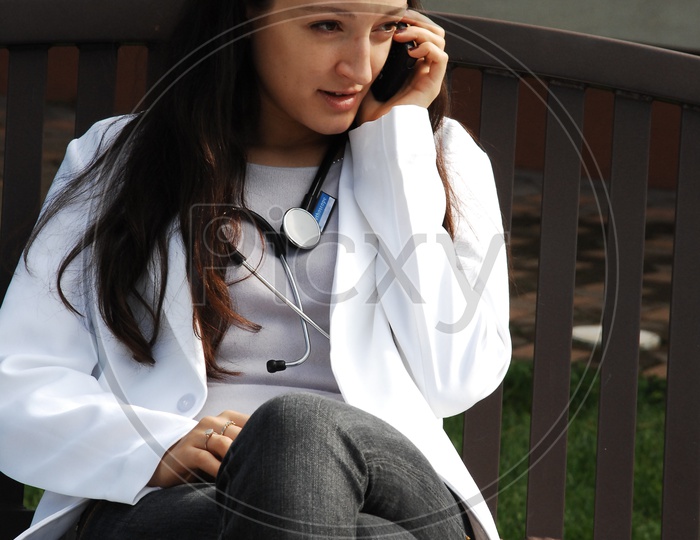 A female doctor wearing white coat with stethoscope talking over the mobile