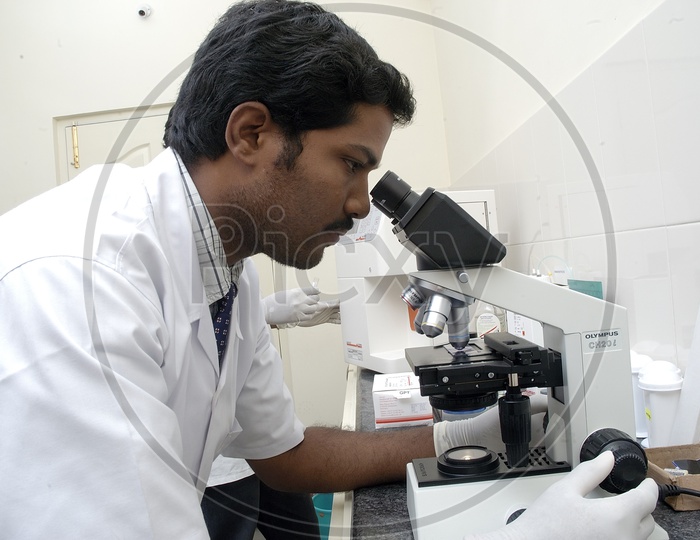 A Male Doctor Looking through a Microscope at Medical Lab