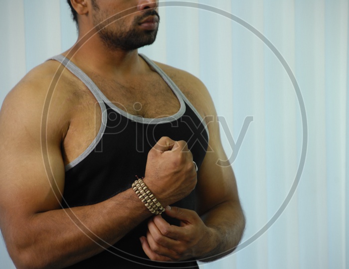 Muscled man wearing vest flexing his muscles in a Gym