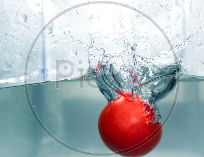 Splash made by dropping a red tomato in clear water