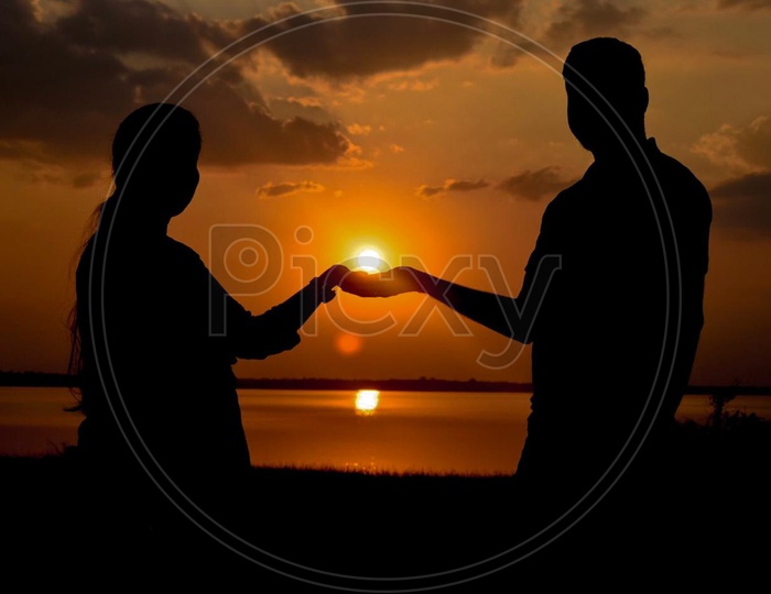 Silhouette Of a Couple Holding Hands Over a Sunset On a Beach