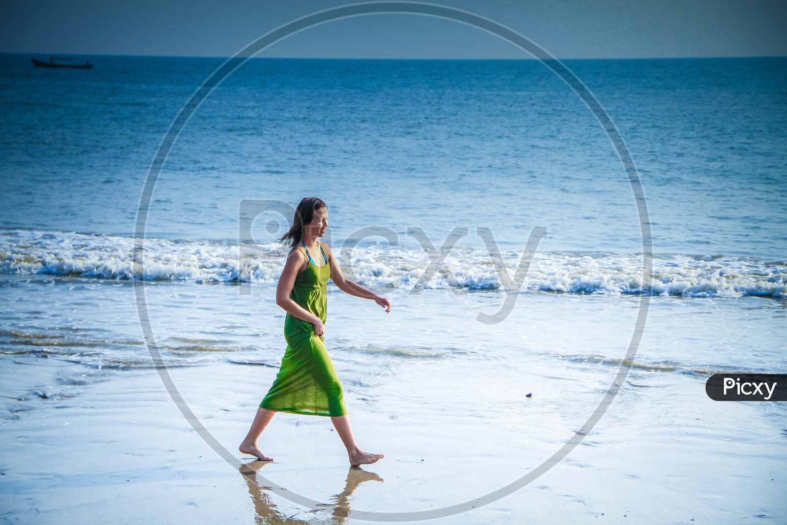 A Lady Walking Along A Beach With Beach Waves And  Blue Sea in Background