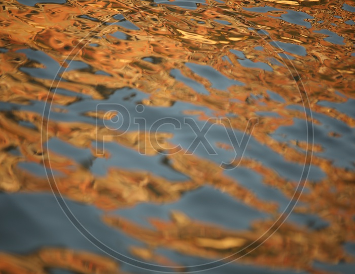 A Closeup Shot Of a Ripples on Water Surface With Luminous Gold Colour of Sun