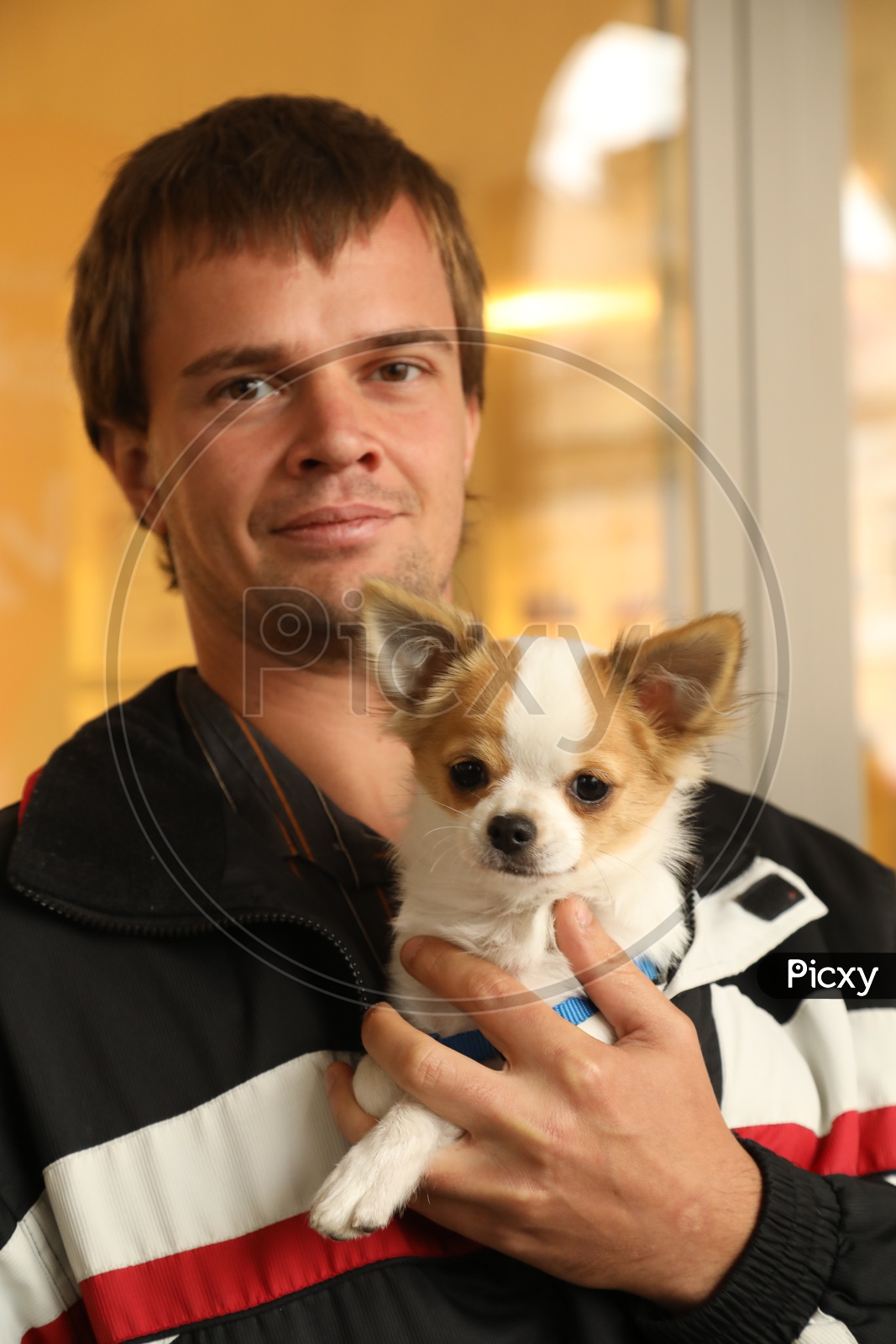 A man smiling and holding a dog in his hand