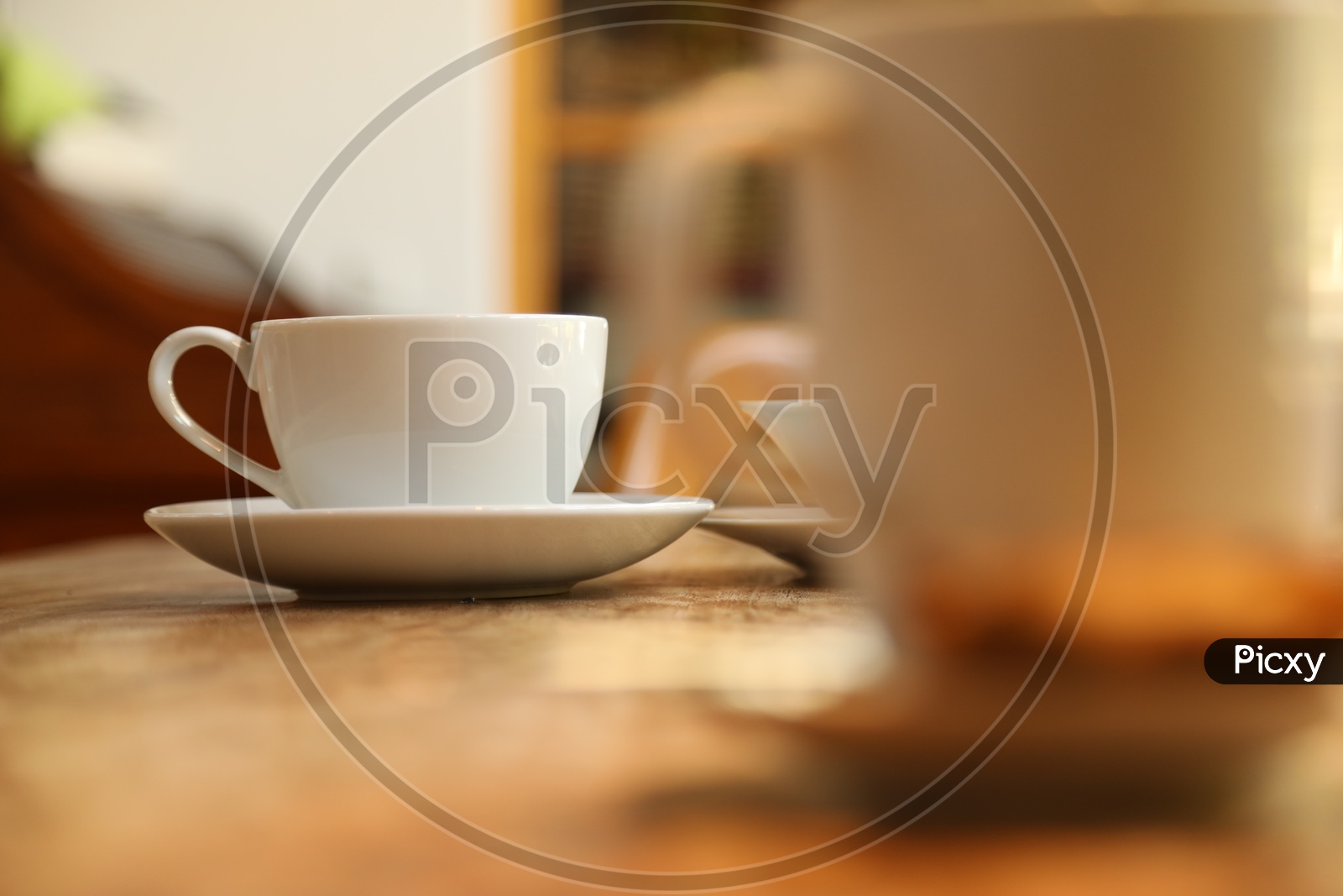 A white cup and saucer on the wooden table