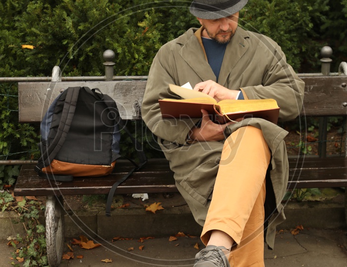 A man sitting on a bench and reading a book