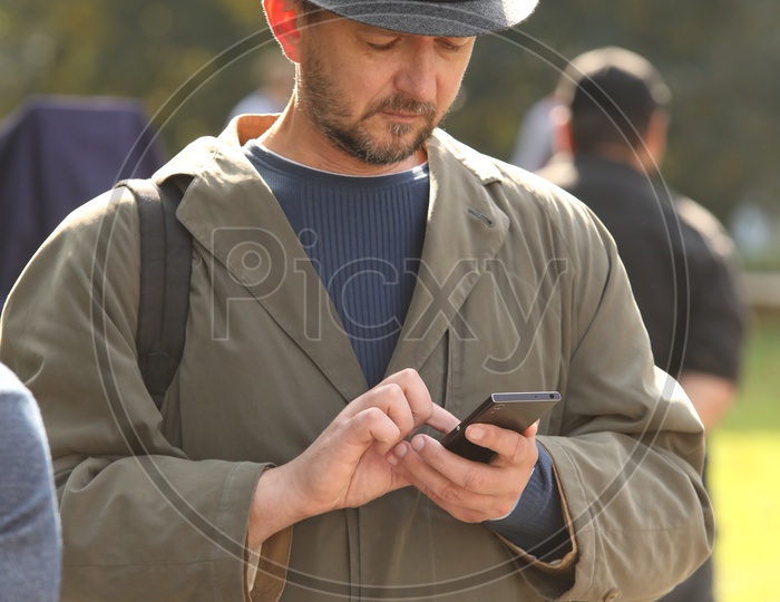 A foriegner man with black hat checking his mobile phone
