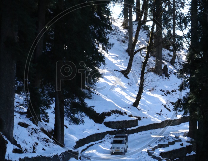 A moving vehicle in the road covered with snow in the hills