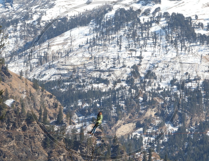 A man sliding by the wire in the mountains