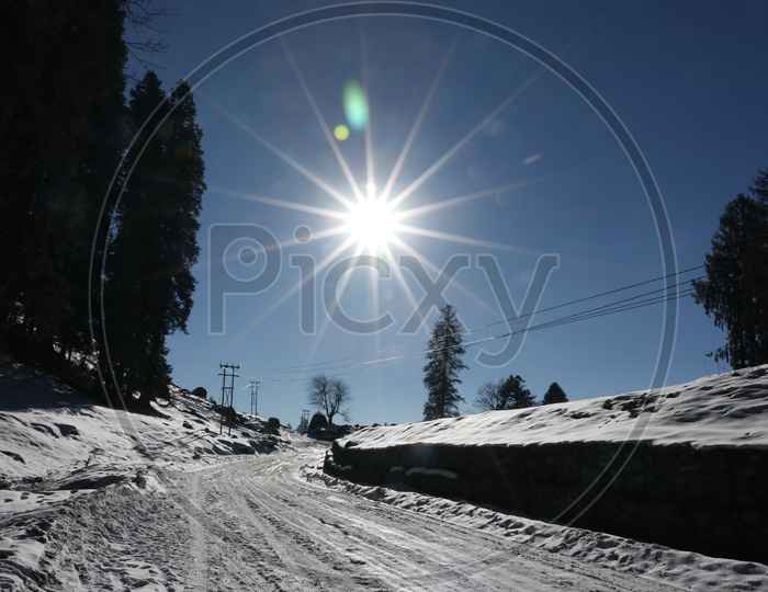 A road full of snow in the hills with bright sun