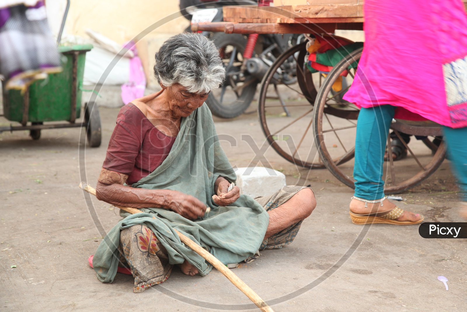 Old woman beggar counting money on a road