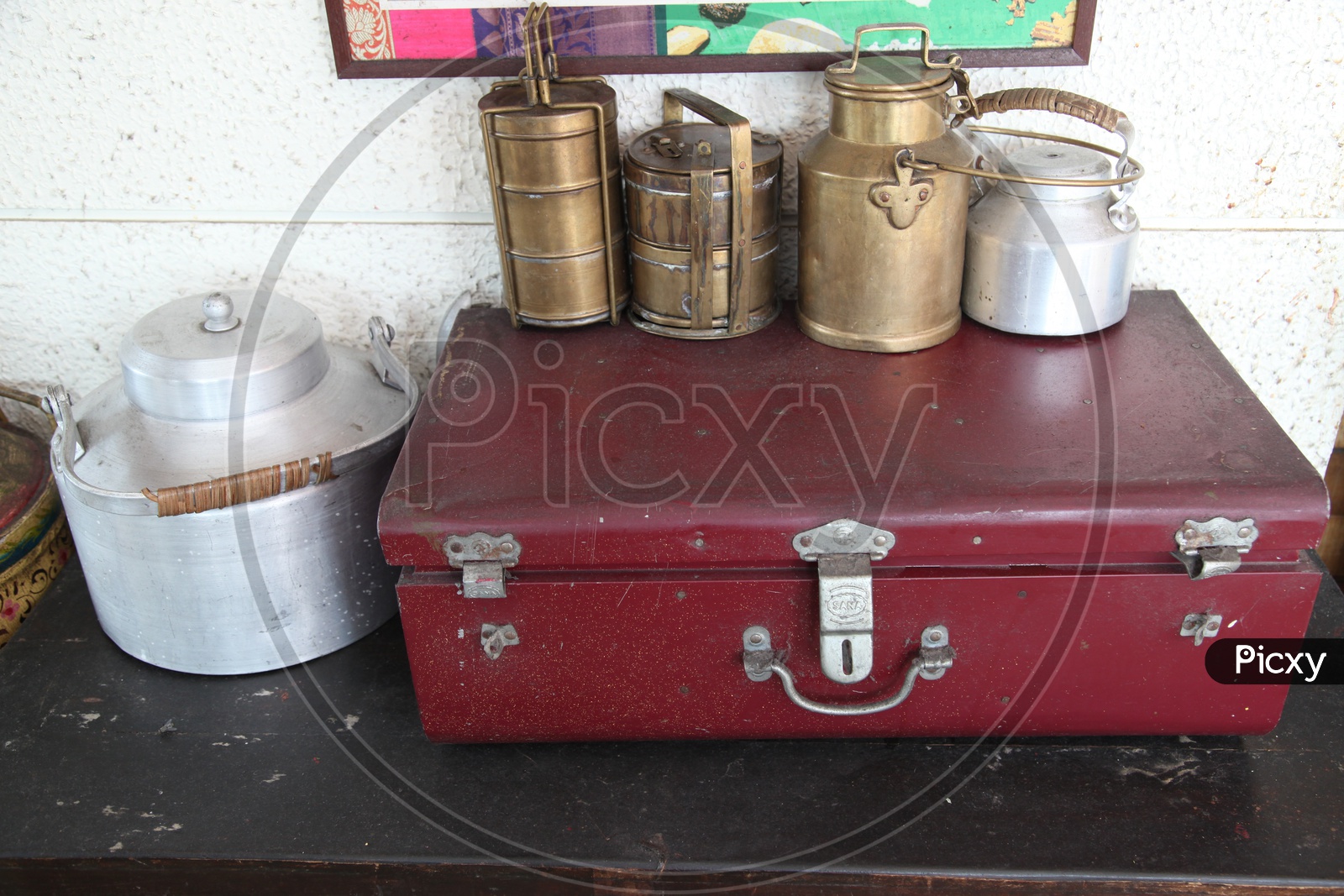 Brass indian traditional lunch boxes and aluminium milk cans and a trunk