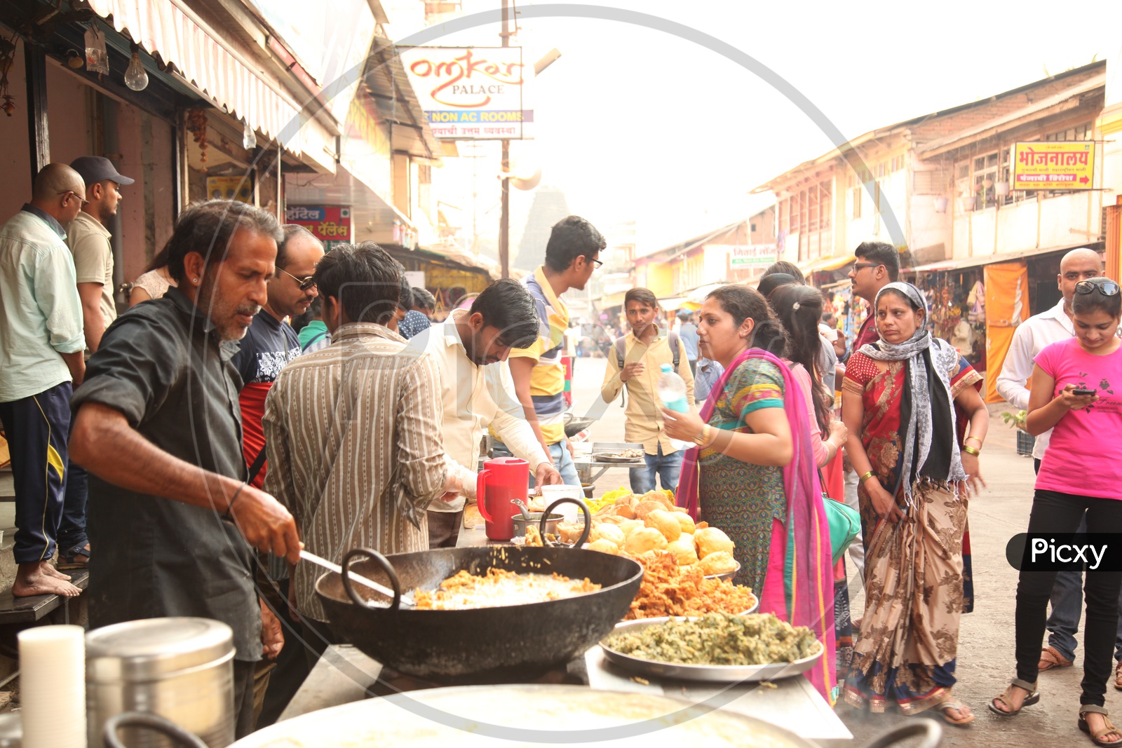 A man cooking Pakodi in a street full of people