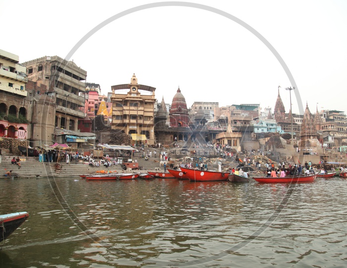 Boats in a river with temples and buildings in the background