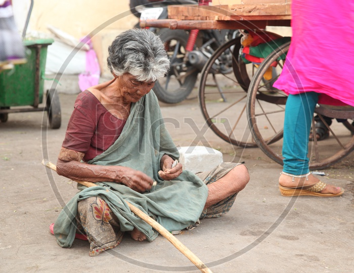 Old woman beggar counting money on a road