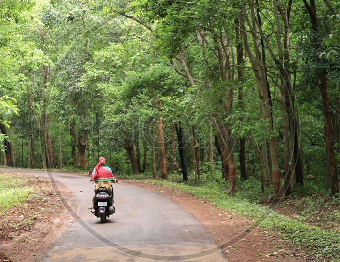 A woman riding a scooty on the road