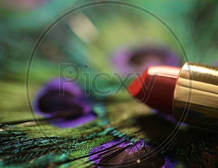 Lipstick With Peacock Feather Bokeh Background