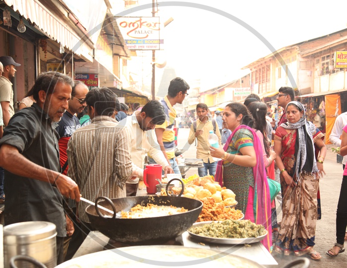 A man cooking Pakodi in a street full of people