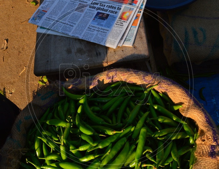 Green chillies in a sack and an english newspaper by the side