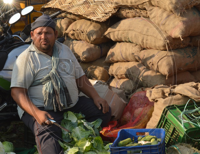 A man chopping the extra cabbage leaves in a market