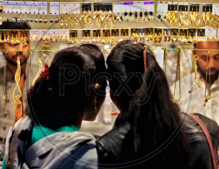 a couple of women looking at grooming jewellery on streets