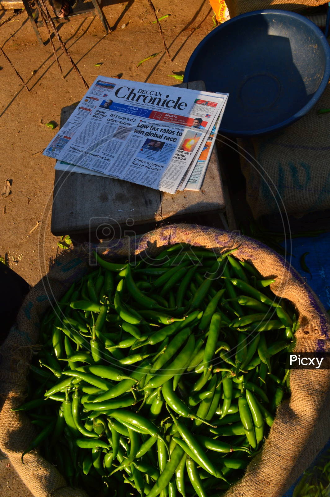 Green chillies in a sack and an english newspaper by the side