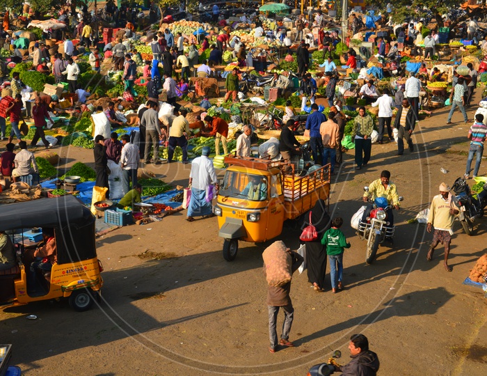 Vegetables getting unloaded from vans and autos in a market
