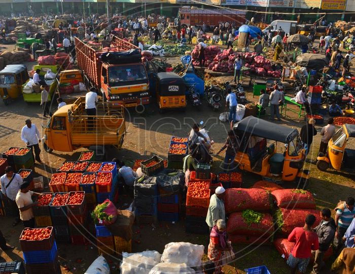 Vegetables getting unloaded from vans and autos in a market
