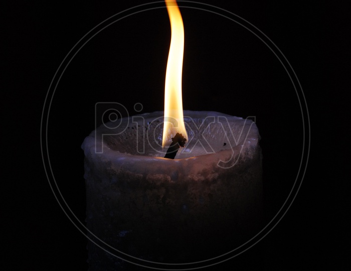 A lit candle with a black background