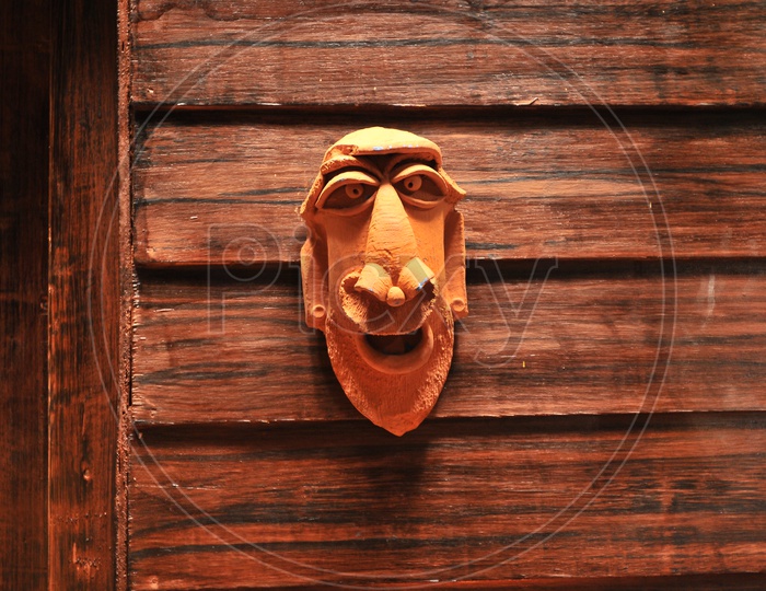 An earthen face statue on a wooden backdrop