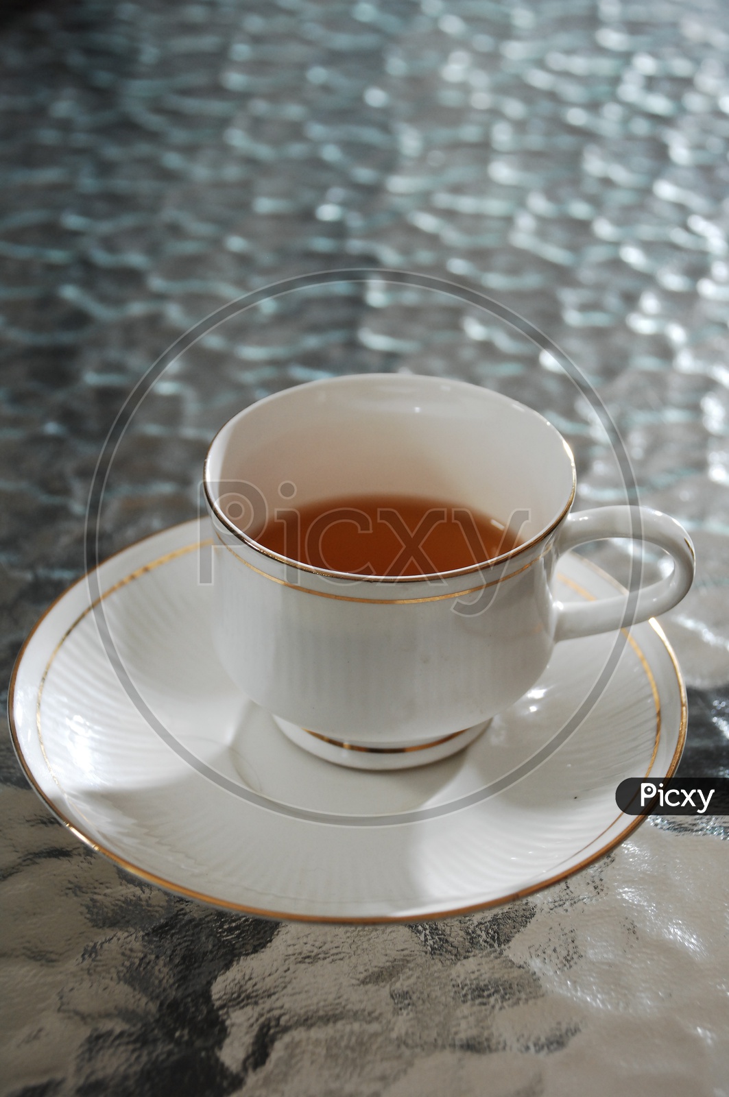 A ceramic white cup of black tea on a saucer