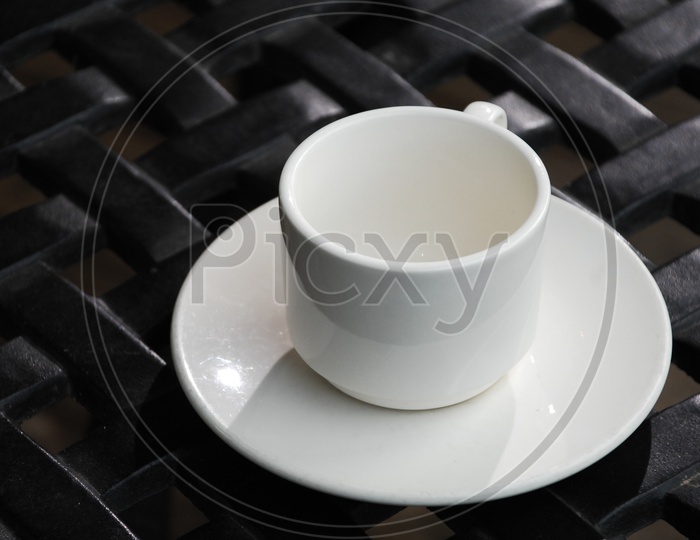 A white tea cup on a saucer with a black background