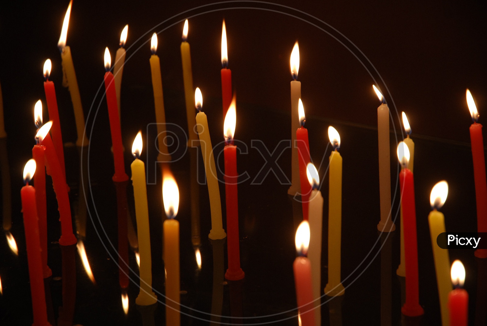 Colourful candles lit in a black background