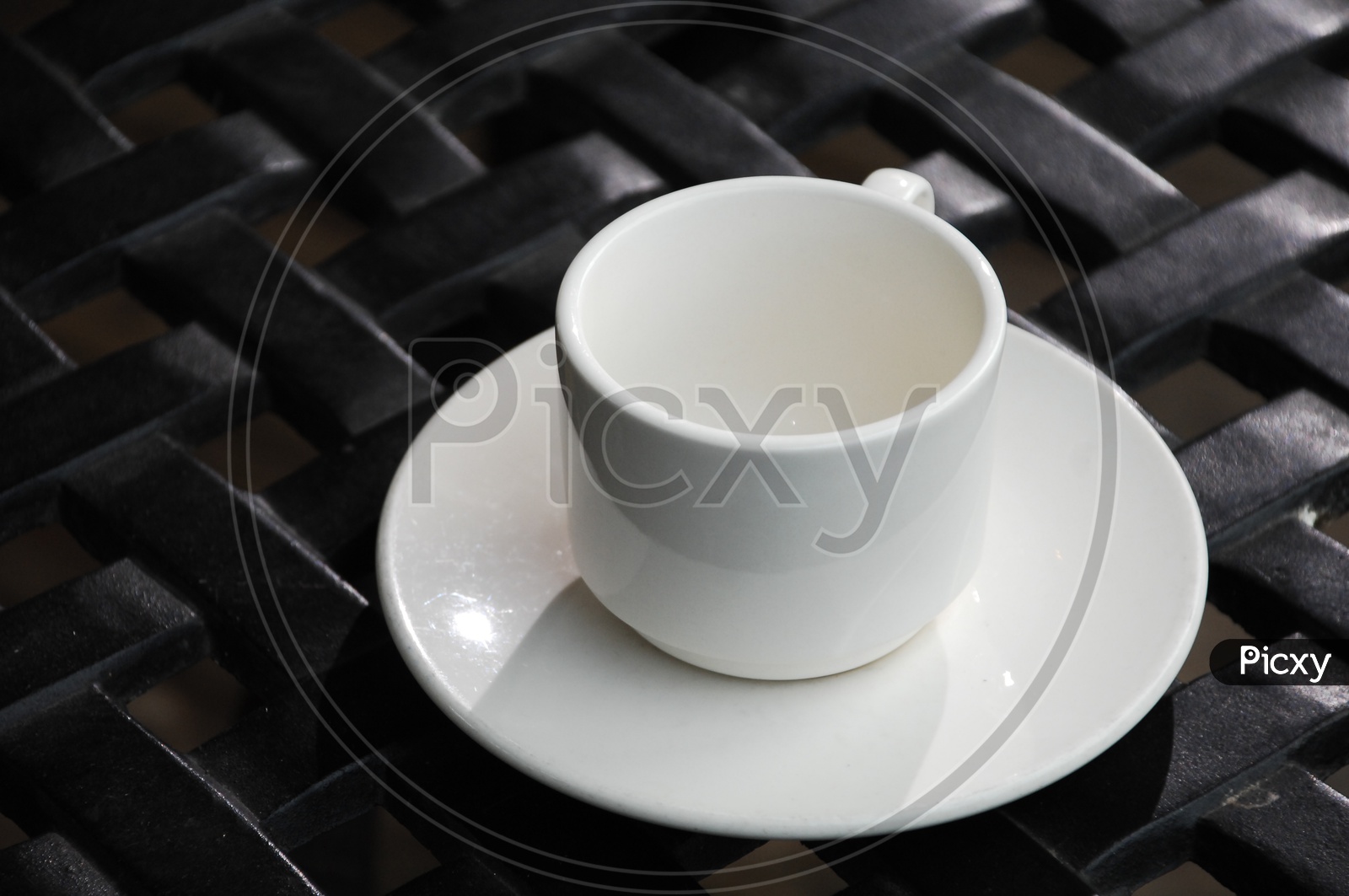 A white tea cup on a saucer with a black background