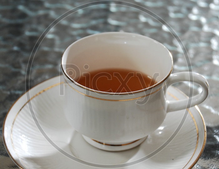 A ceramic white cup of black tea on a saucer