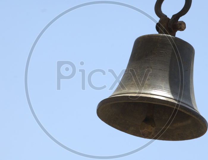 Hanging metal bell with sky background