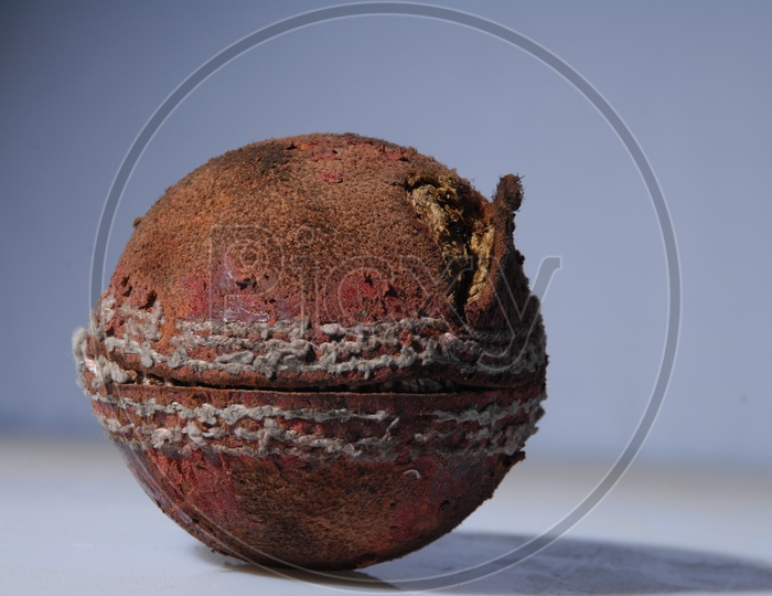 A used and worn out cricket ball in white background