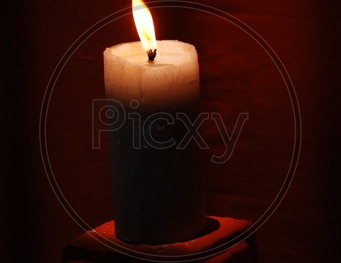 A lit candle with a red background