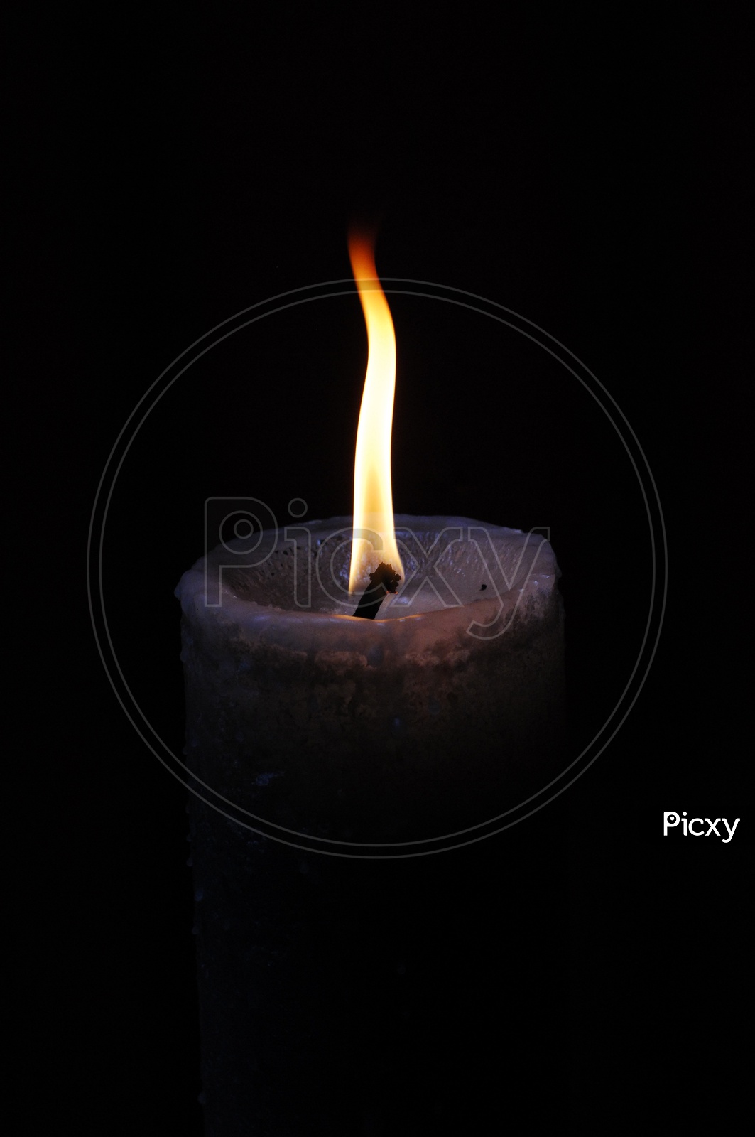 A lit candle with a black background