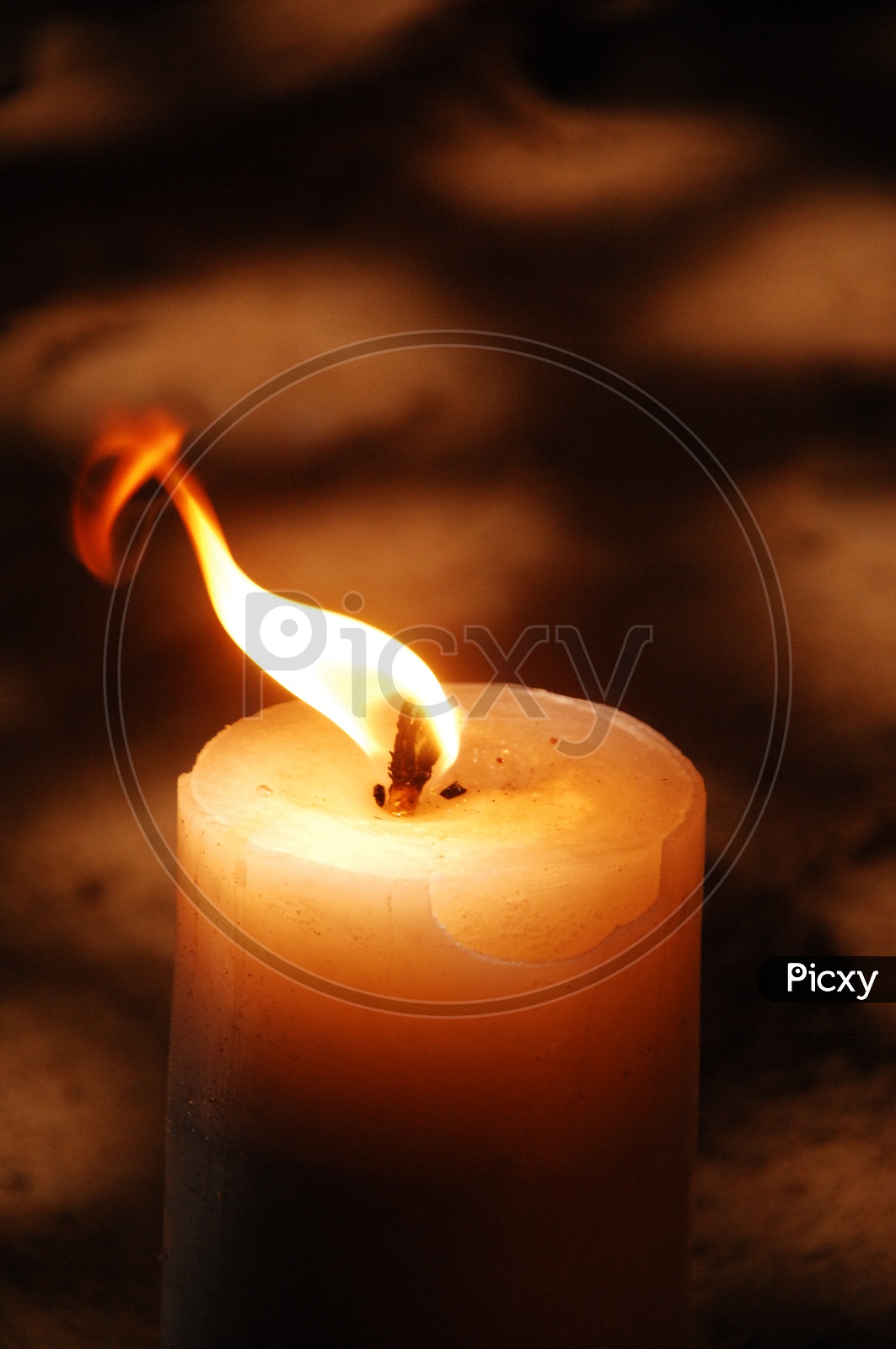 A lit candle with a dark background