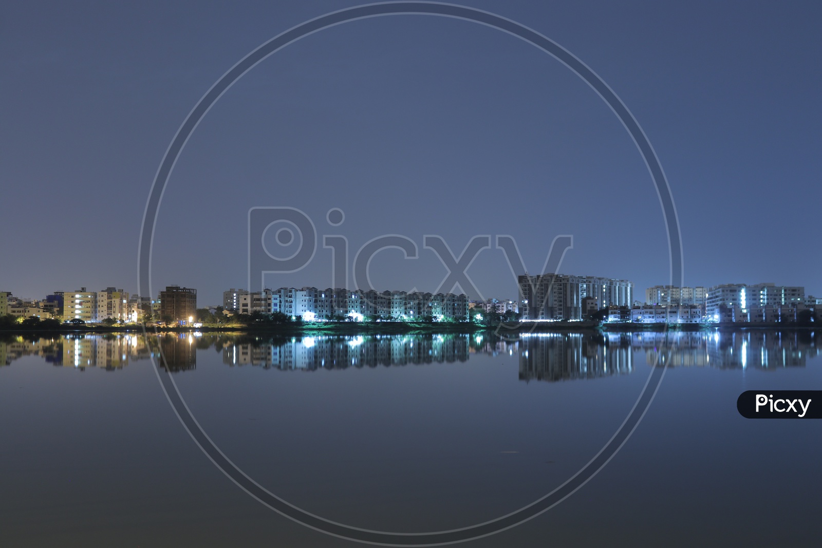 Night view of reflections of buildings in the water at Pragathi Nagar Lake