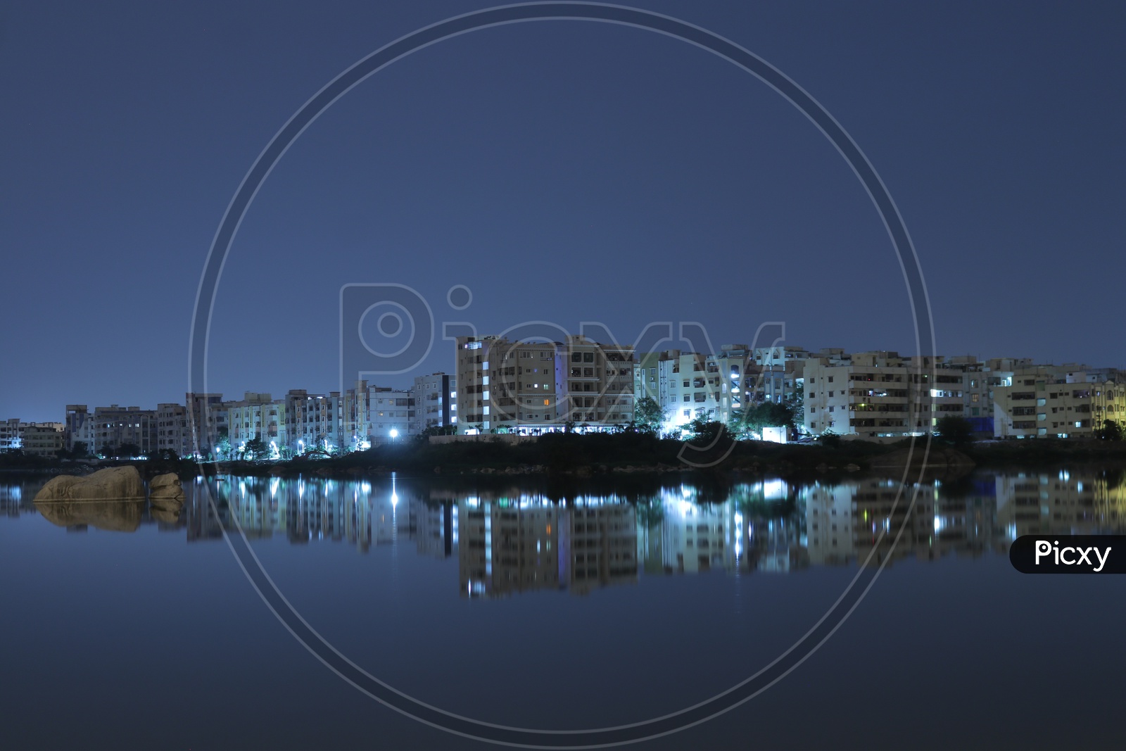 Night view of reflections of buildings in the water at Pragathi Nagar Lake